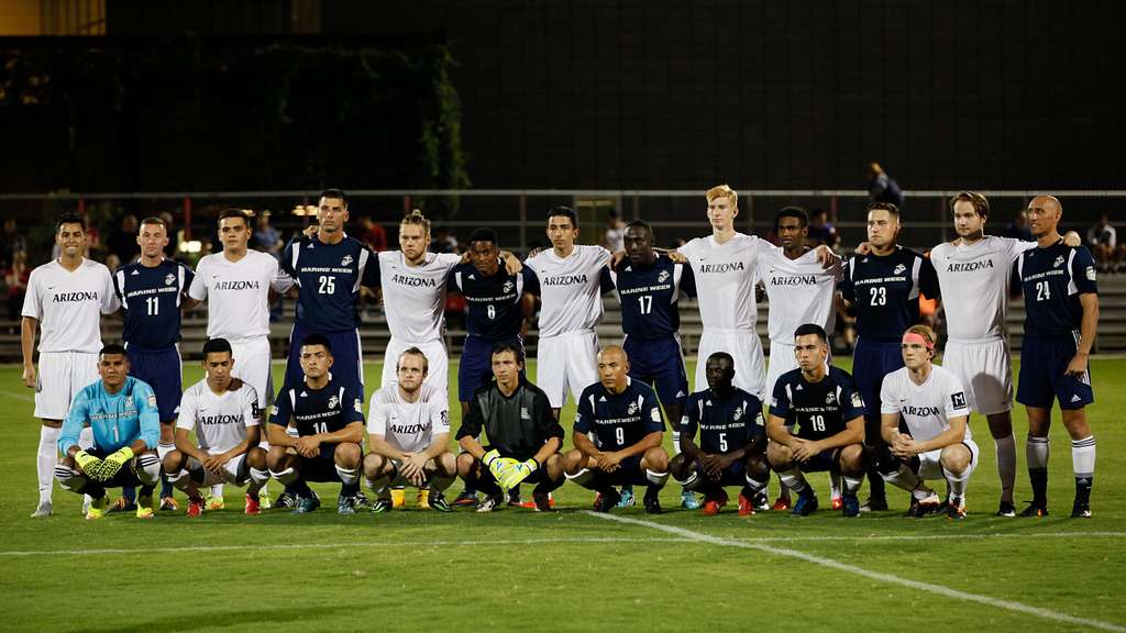 Dos equipos de fútbol posando juntos antes de un partido nocturno en Estados Unidos.