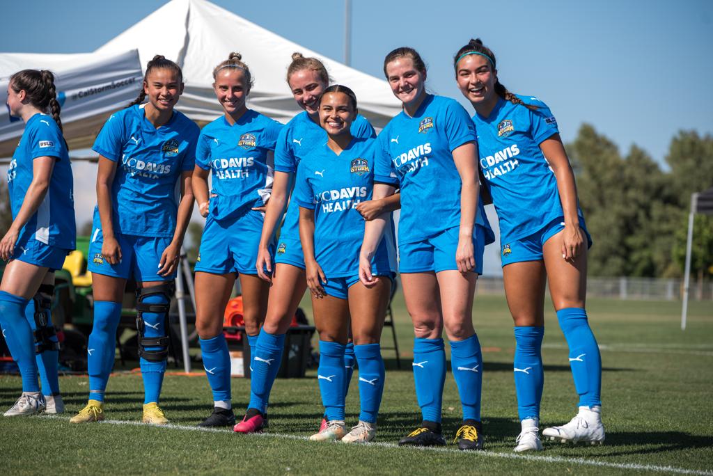 Jugadoras del equipo femenino de fútbol Sacramento Storm posando sonrientes antes del partido