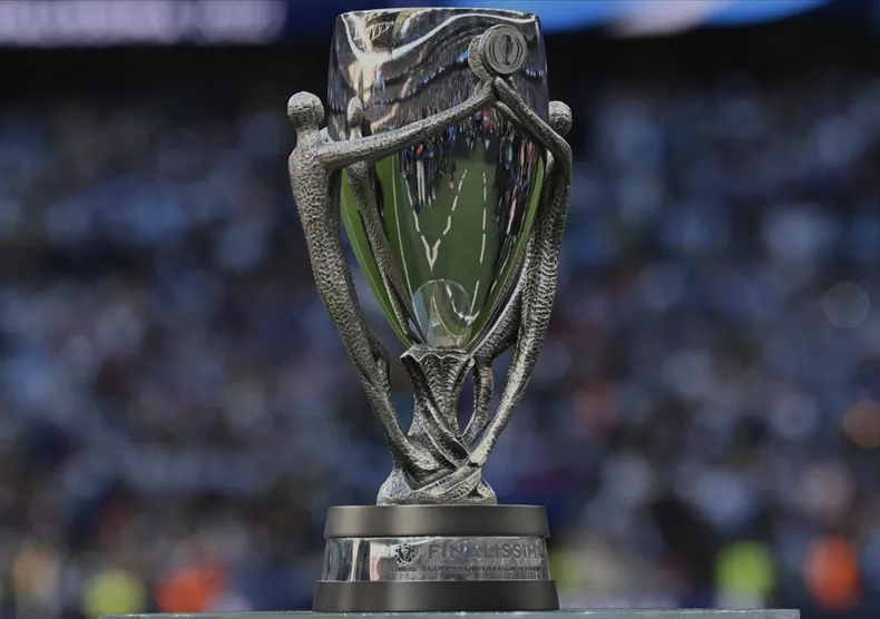 Primer plano del trofeo Finalissima sobre el campo, con estadio de fondo desenfocado