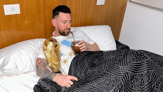 Lionel Messi tomando mate en la cama junto a la Copa del Mundo