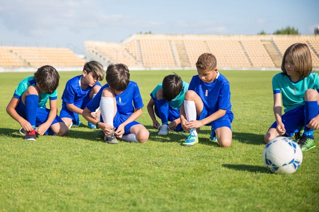 Niños futbolistas atándose los cordones antes de un partido en un estadio