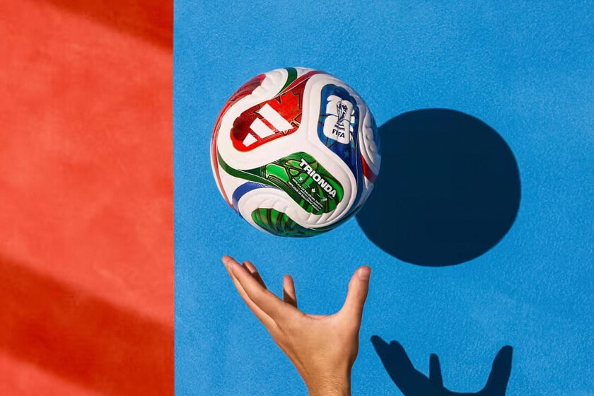 Pelota Trionda del Mundial 2026 suspendida en el aire sobre fondo azul y rojo