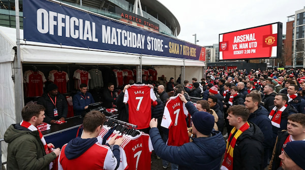 Aficionados comprando la camiseta número 7 de Saka, una de las más vendidas en 2025. Aficionados del Arsenal comprando camisetas oficiales de Saka en la tienda del estadio antes de un partido.