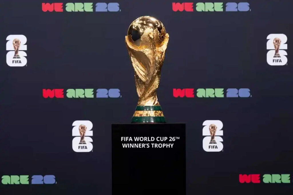 Trofeo oficial del Mundial 2026 exhibido frente a un fondo con el lema “We Are 26” de la FIFA.
