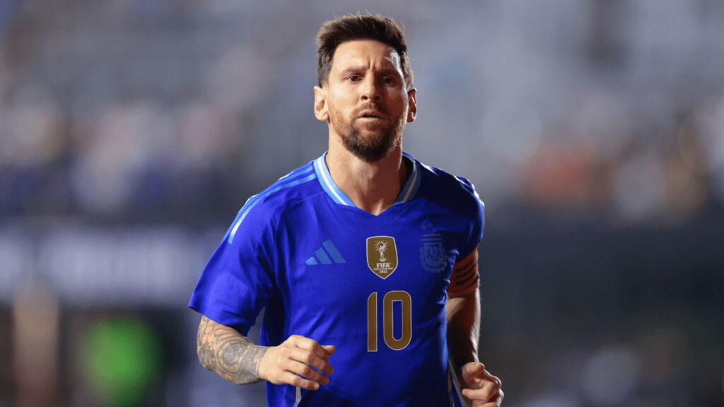 Messi con camiseta azul corriendo en el campo durante un partido internacional.