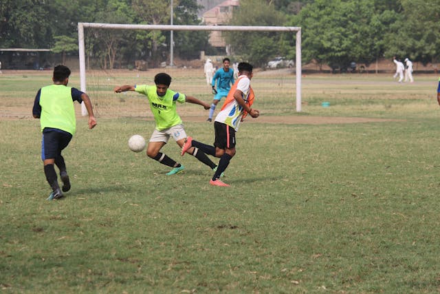 Jugadores jóvenes disputando un partido de fútbol en un campo al aire libre durante un entrenamiento.