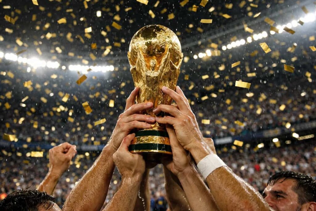 Jugadores levantando el trofeo del Mundial bajo una lluvia de confeti dorado, símbolo del premio récord que recibirá el campeón en 2026.
