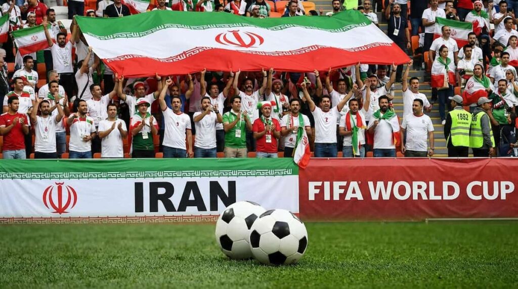 Aficionados de Irán en un estadio con banderas durante un partido internacional de fútbol